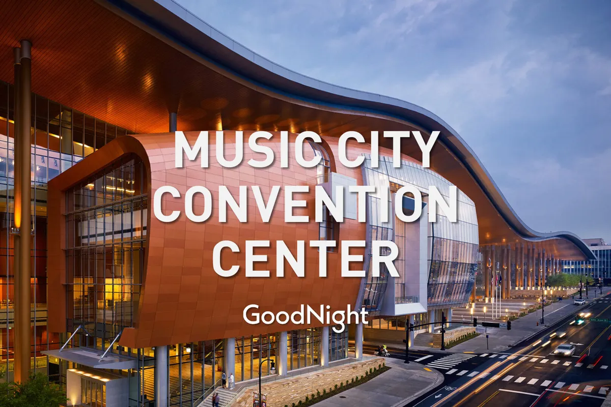 This image features the exterior of a modern conference and event venue with striking curved architecture, large glass windows, and dynamic nighttime lighting. The scene is vibrant, capturing the energy of attendees arriving for conferences, exhibitions, or public gatherings.