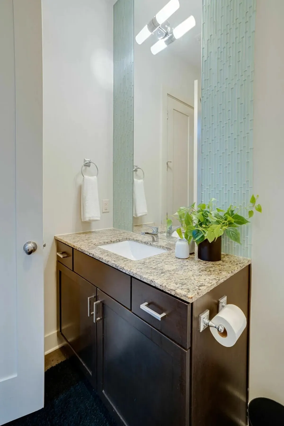 A serene bathroom featuring a granite countertop, modern faucet, decorative wall tiles, and a potted plant, creating a tranquil atmosphere for self-care routines and private moments.
