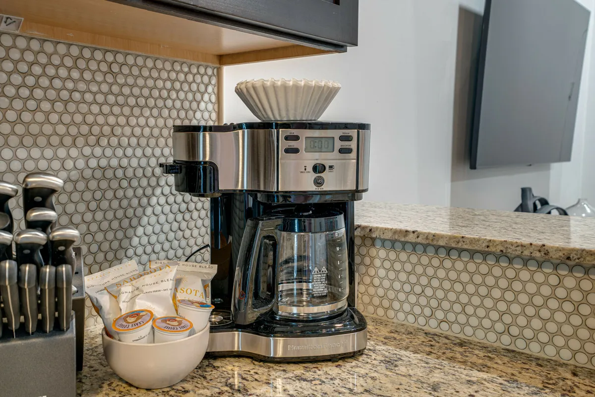 A cozy kitchen nook centered around a granite countertop, coffee maker, coffee cups, and a knife set. The scene emphasizes everyday essentials and the joy of preparing breakfast or snacks.